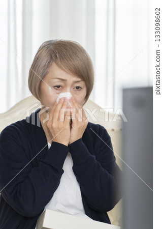 一位老婦人在客廳一邊看悲傷的電視節目一邊哭泣 一位老婦人在客廳一邊看悲傷的電視節目一邊哭泣 133098602