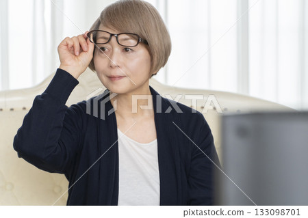 一位戴著眼鏡的老婦人在客廳看電視 一位戴著眼鏡的老婦人在客廳看電視 133098701