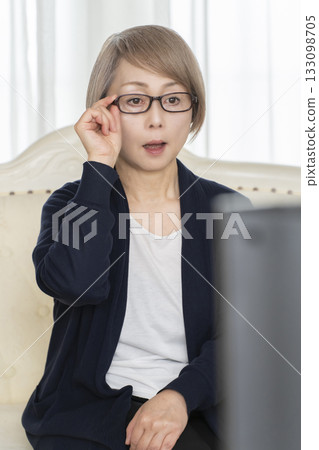 一位戴著眼鏡的老婦人在客廳看電視 133098705