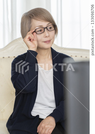 Senior woman wearing glasses watching TV in the living room 133098706