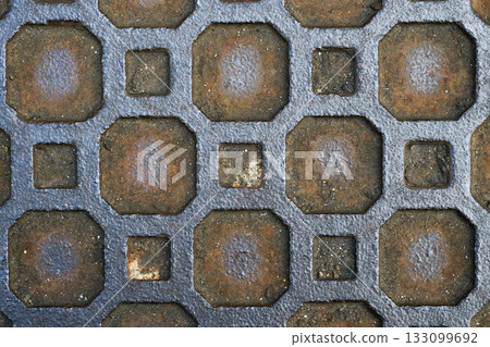 Geometric pattern on a rusty old manhole cover 133099692