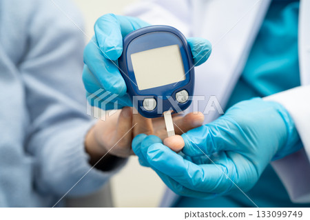 Asian doctor using digital glucose meter for check sample blood sugar level to treatment diabetes. 133099749
