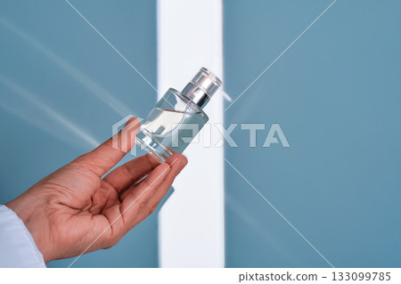 Hand holding perfume bottle with light shadows Hand holding perfume bottle with light shadows 133099785