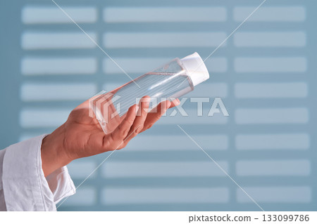 Person holding skincare toner bottle for beauty routine 133099786