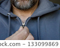 Man zipping gray hoodie close-up 133099869