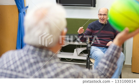 Man in wheelchair playing ball with senior 133100014
