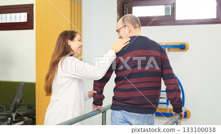 Woman assisting elder man during physical therapy session 133100038