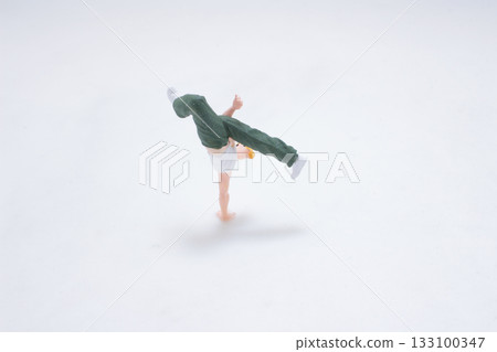 Tiny Figure Doing Handstand Move in White Studio Background 133100347