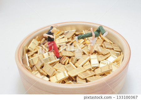 Miniature People Climbing Gold Bars in a Bowl of Wealth Miniature People Climbing Gold Bars in a Bowl of Wealth 133100367
