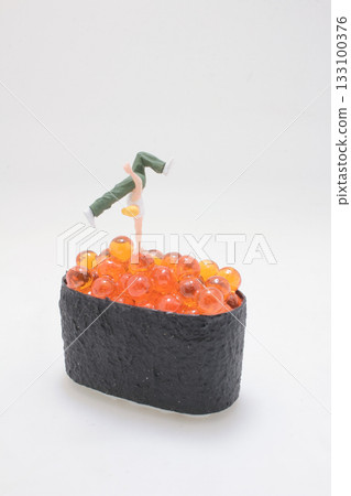Miniature Figure Doing Handstand on Orange Fish Roe Miniature Figure Doing Handstand on Orange Fish Roe 133100376
