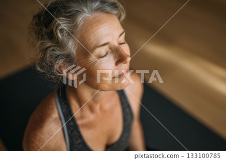 Older woman sitting in indoor meditation pose Older woman sitting in indoor meditation pose 133100785