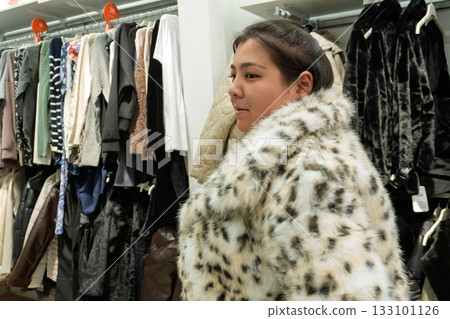 Woman Trying On Faux Fur Coat in Clothing Store Woman Trying On Faux Fur Coat in Clothing Store 133101126