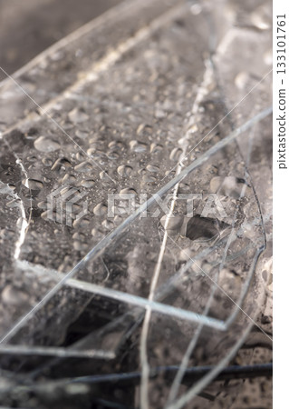 broken wet old glass lies on a black slate board with an uneven texture, pieces of broken transparent glass covered with water close up broken wet old glass lies on a black slate board with an uneven texture, pieces of broken transparent glass covered with water close up 133101761