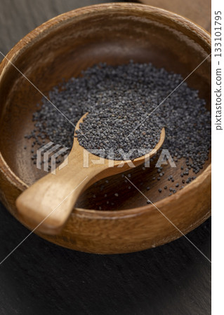 wooden bowl used in the manufacture of confectionery, a large amount of poppy seeds in a wooden bowl with a spoon wooden bowl used in the manufacture of confectionery, a large amount of poppy seeds in a wooden bowl with a spoon 133101795
