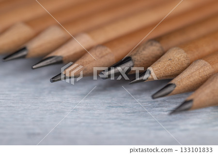 wooden pencils with lead on blue corrugated paper, several monochrome pencils for sketches or graphic work are in a row. wooden pencils with lead on blue corrugated paper, several monochrome pencils for sketches or graphic work are in a row. 133101833