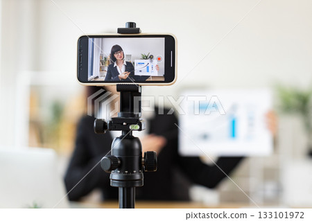 Caucasian young adult woman sitting at table holding presentation while recording blog. Concept of business, communication, and content creation. Caucasian young adult woman sitting at table holding presentation while recording blog. Concept of business, communication, and content creation. 133101972