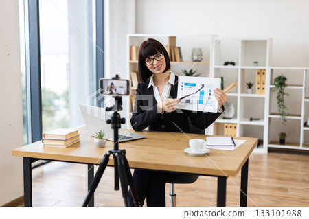 Caucasian woman presenting business data in office, recording blog or video with professional equipment 133101988