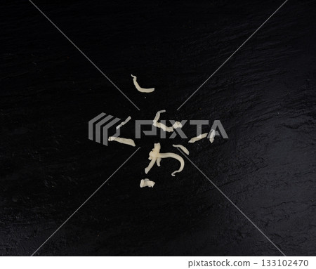 Grated mozzarella cheese on black background. Shredded mozarella texture 133102470