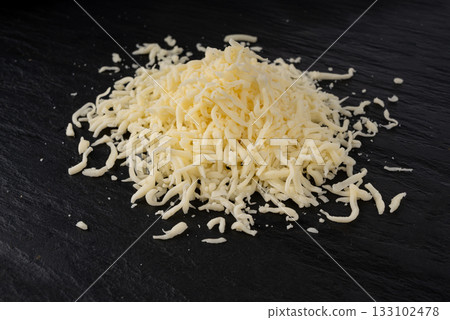 Grated mozzarella cheese on black background. Shredded mozarella texture 133102478