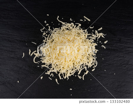 Grated mozzarella cheese on black background. Shredded mozarella texture 133102480