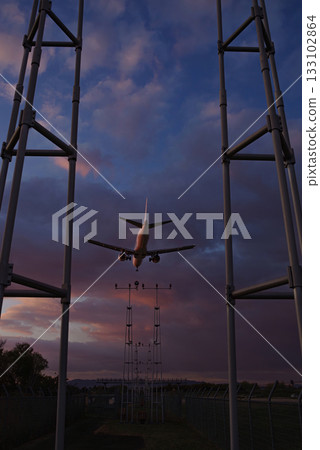 黃昏時分，一架飛機飛過一盞引導燈。 133102864