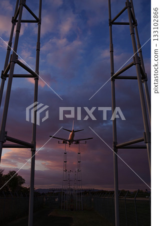 An airplane flying over a guide light at dusk 133102866