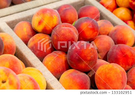 Lots of fresh peaches in a plastic tray on the counter of a grocery store 133102951