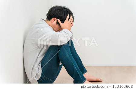 一位年輕的亞洲男子雙手抱頭坐著（失敗、絕望、擔憂、後悔） 133103668