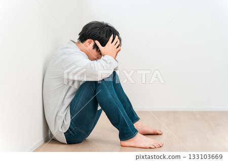 一位年輕的亞洲男子雙手抱頭坐著（失敗、絕望、擔憂、後悔） 133103669