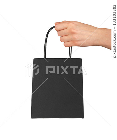 Hand holding small black paper bag, concept of shopping, beauty and luxury product purchase, minimal Hand holding small black paper bag, concept of shopping, beauty and luxury product purchase, minimal 133103882