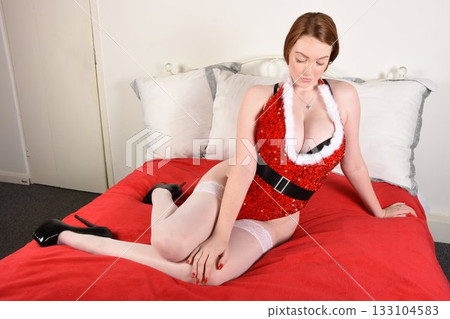 Beautiful redhead girl dressed as a sexy Santa, posing on her bed in an old house Beautiful redhead girl dressed as a sexy Santa, posing on her bed in an old house 133104583