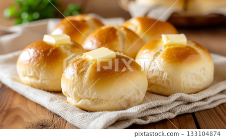 Warm buttered Parker House rolls arranged on rustic linen napkin showcasing golden bakery perfection 133104874