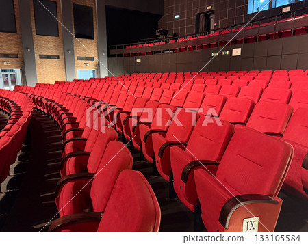 Empty auditorium with red seats and warm light. Architecture, expectation, and cultural space symbolizing art, anticipation, and human connection. 133105584