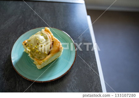 Pistachio cinnamon roll on an artisan plate in a home kitchen, top view. Natural light, simple homemade food setup. Concept of breakfast, pastry, comfort, homemade. 133107280