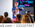 Speaker presents a colorful tech talk to audience with coding on screen 133107497