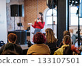 Speaker in red top presents to engaged audience during workshop in brick loft 133107501