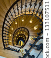 Spiral staircase view from above with ornate iron railing and warm hanging lamps, grand design 133107511