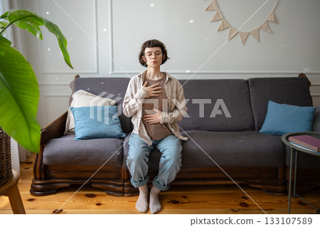 Calm woman breathing slowly with palms on torso, diaphragmatic control for inner balance. Inhaling 133107589