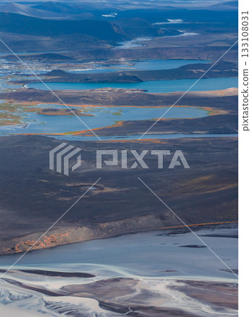 Aerial view of blue lakes amid dark volcanic terrain, with glacial streams in the foreground and rolling hills in the distant Icelandic highlands. Aerial view of blue lakes amid dark volcanic terrain, with glacial streams in the foreground and rolling hills in the distant Icelandic highlands. 133108031