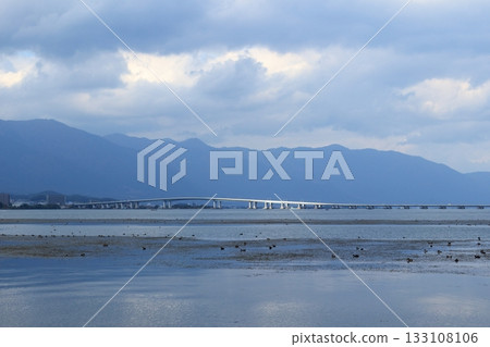 陽光透過雲層照射進來，映照在琵琶湖大橋上，使其顯得閃閃發光，如同金屬一般。 133108106