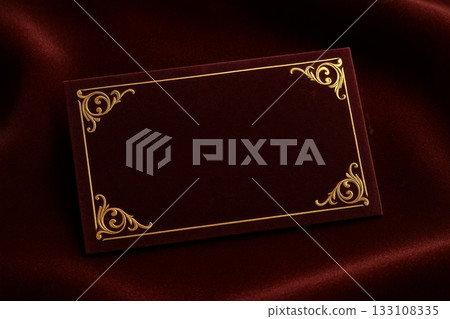 Dark red velvet business card with gold ornate frame on fabric background. Elegant vintage mockup for luxury branding or invitation design. 133108335