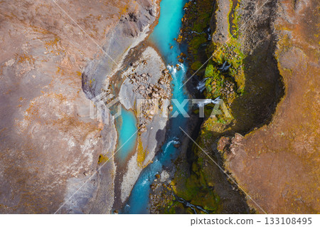 Turquoise river flows through a rugged Icelandic canyon with moss covered cliffs, rocky terrain, and cascading waterfalls creating dynamic movement. Turquoise river flows through a rugged Icelandic canyon with moss covered cliffs, rocky terrain, and cascading waterfalls creating dynamic movement. 133108495