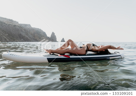 Woman Paddleboard Ocean Relaxing on Paddleboard in Sea with Cliffs in Background Woman Paddleboard Ocean Relaxing on Paddleboard in Sea with Cliffs in Background 133109101