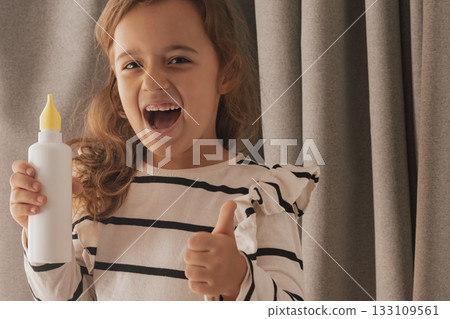 Smiling while using a nasal spray and giving a confident thumbs up sign Smiling while using a nasal spray and giving a confident thumbs up sign 133109561