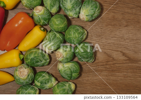 Colorful combination of brussel sprouts and bell peppers on a wood background Colorful combination of brussel sprouts and bell peppers on a wood background 133109564