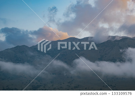 Scenic view of a mediterranean mountain range covered by mist and soft light Scenic view of a mediterranean mountain range covered by mist and soft light 133109576