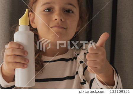 Happy demonstration: child showing approval while holding an unbranded nasal spray Happy demonstration: child showing approval while holding an unbranded nasal spray 133109591