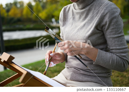 Close-up of artist hands holding painting brushes. Close-up of artist hands holding painting brushes. 133110667
