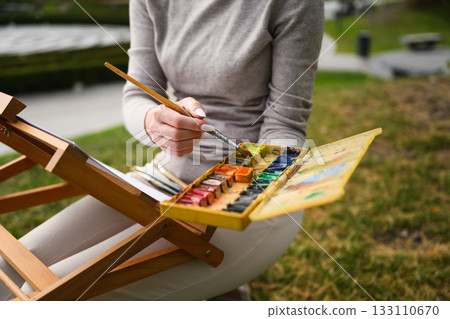Close-up of artist mixing colors on watercolor palette. 133110670