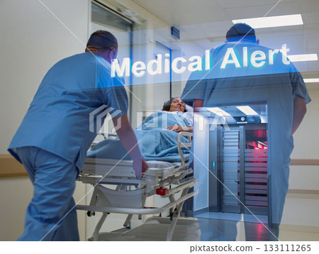 Medical alert urgent patient transport in hospital corridor. A male medical professional in blue scrubs is urgently transporting a female patient on a stretcher through a hospital corridor. Medical alert urgent patient transport in hospital corridor. A male medical professional in blue scrubs is urgently transporting a female patient on a stretcher through a hospital corridor. 133111265
